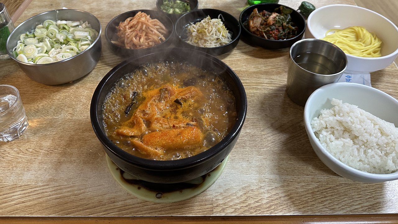 뚝배기에 끓는 추어탕과 반찬, 밥이 차려진 식탁